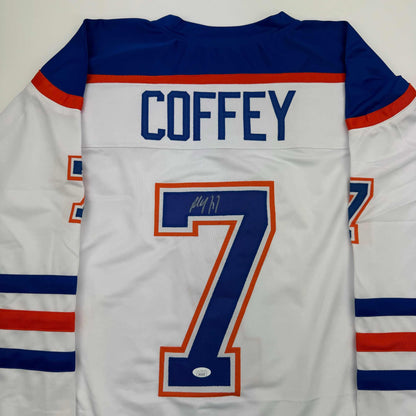 Back view of white Edmonton Oilers hockey jersey with "COFFEY" name and number 7 in blue and orange, autographed.
