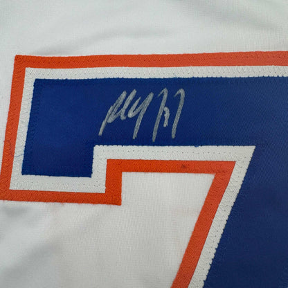 Close-up of handwritten signature on blue panel of white Edmonton Oilers hockey jersey with orange and gray trim.