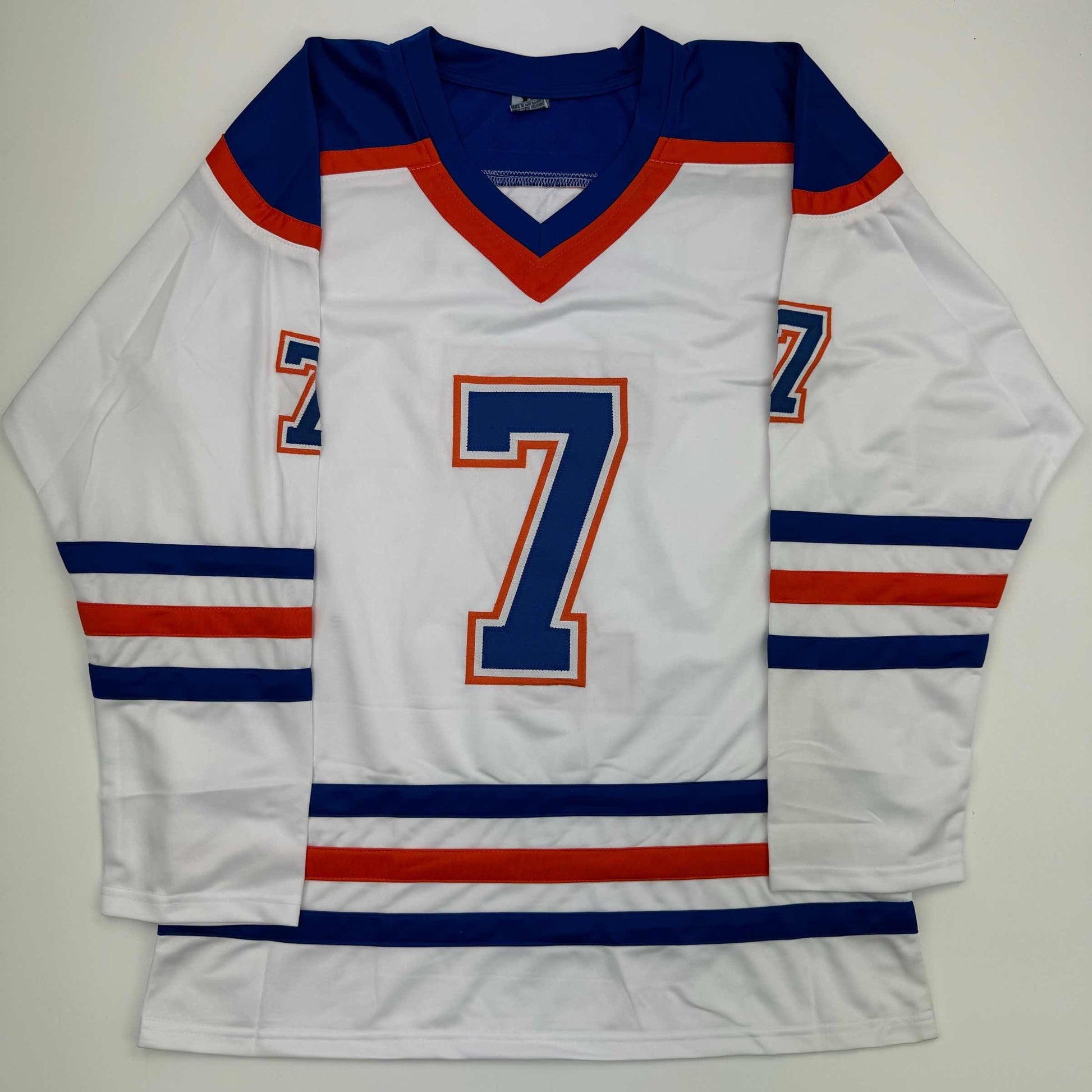 White Edmonton Oilers hockey jersey number 7 with navy blue and red trim, displayed flat against gray background.