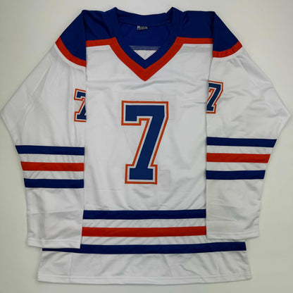 White Edmonton Oilers hockey jersey number 7 with navy blue and red trim, displayed flat against gray background.