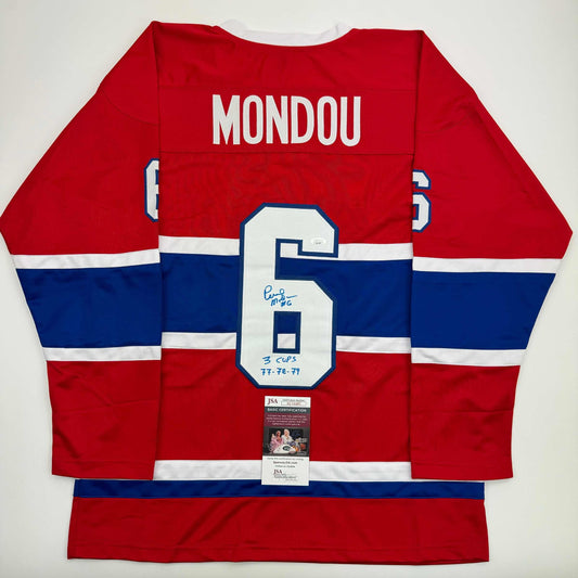 Red, white, and blue Montreal Canadiens hockey jersey displayed flat, showing back with "MONDOU" and number 5, signed with "3 CUPS 77-78-79" notation and JSA certification label.