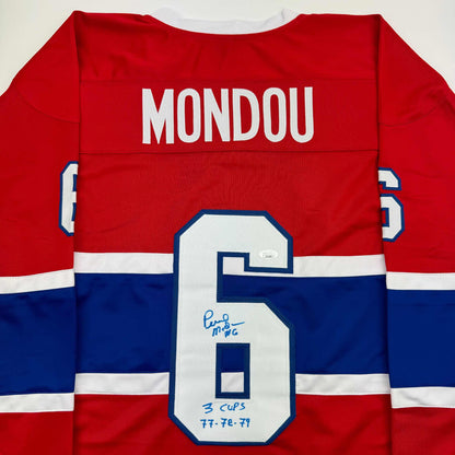 Back view of red, white, and blue Montreal Canadiens hockey jersey with "MONDOU" nameplate and number 6 with handwritten inscription.