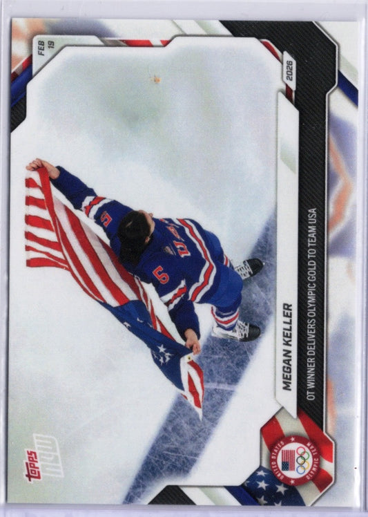 Megan Keller in Team USA blue hockey jersey #5 holds American flag while skating on ice, viewed from above at angle.