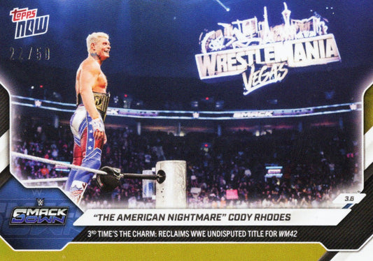 Cody Rhodes stands shirtless in red and blue wrestling attire holding a championship belt at WrestleMania in Las Vegas, Topps Now card with gold foil finish.
