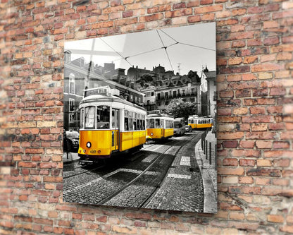 Yellow tram glass art mounted on brick wall, showing selective color street scene with vintage trolley and European architecture.