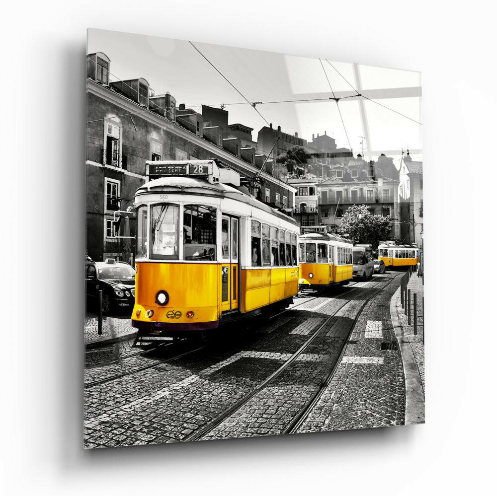 Yellow tram number 28 on cobblestone street in Lisbon with historic buildings and power lines, printed on glass wall panel.