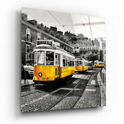 Yellow tram number 28 on cobblestone street in Lisbon with historic buildings and power lines, printed on glass wall panel.