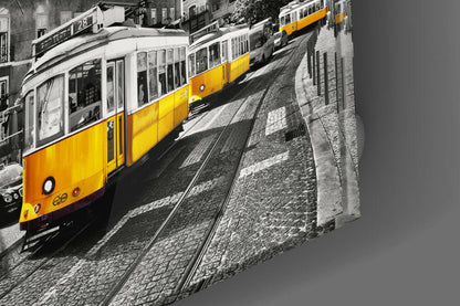 Elevated angled view of yellow tram on cobblestone street with bus and buildings in selective color photograph.