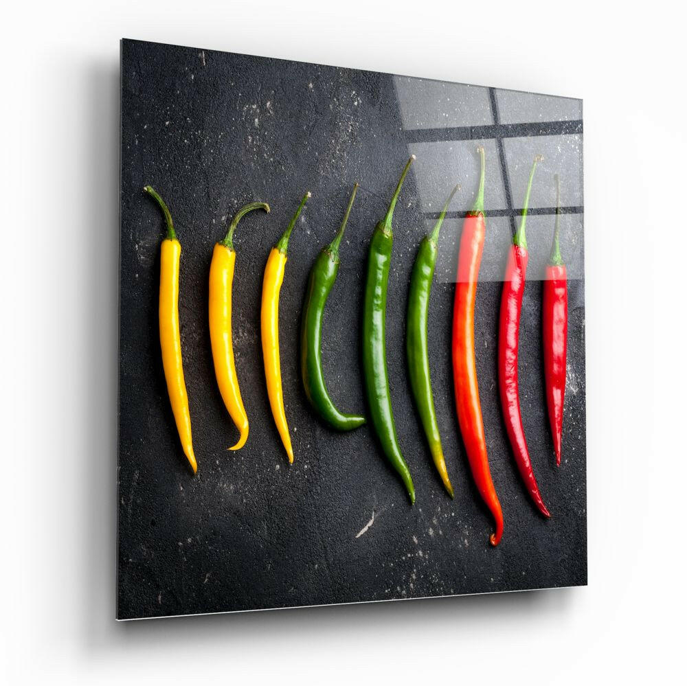 Nine chili peppers arranged in a color gradient from yellow to red on a dark textured glass panel with grid lines, displayed at an angle.