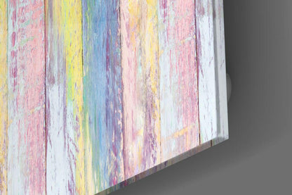 Angled perspective view of glass wall art with pastel rainbow-painted wooden planks in pink, yellow, blue, and white.