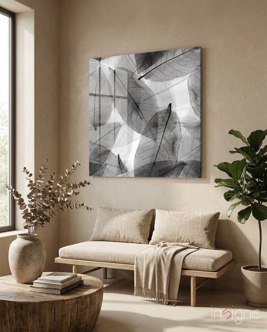 Black and white translucent leaf glass artwork displayed above a beige linen sofa in a minimalist living room interior.