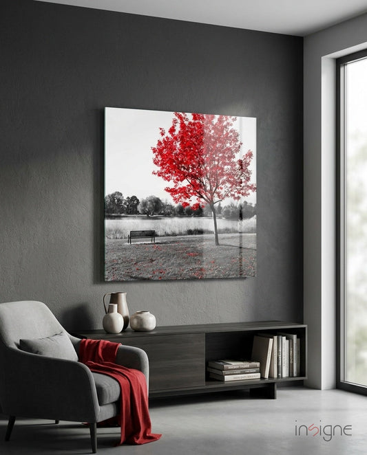 Red Tree Lakeside Bench glass wall art displayed on dark gray wall above black media console in modern living room with gray chair.