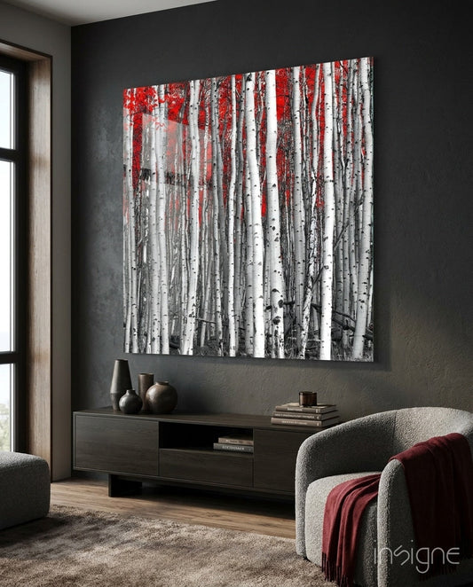 Square glass wall art depicting white birch tree trunks with red autumn foliage displayed above dark media console in modern living room.