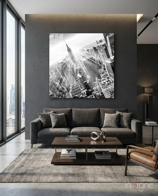 Black and white aerial New York City skyline photograph displayed above gray sofa in modern living room.
