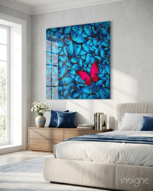 Pink butterfly glass wall art with blue butterfly background displayed above wooden nightstand in modern bedroom.
