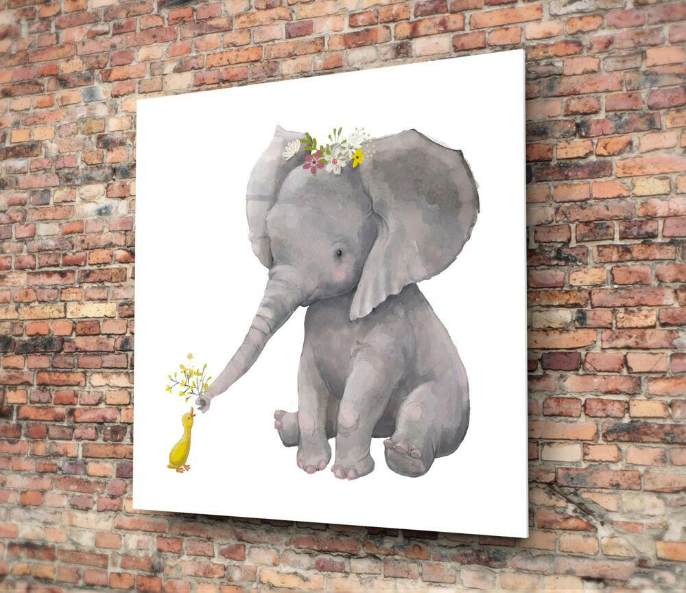 Glass wall art mounted on brick wall showing watercolor illustration of gray elephant with flower crown and small yellow duck holding flowers.