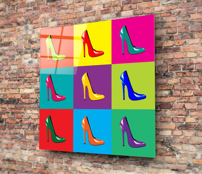 Colorful pop-art style glass wall panel featuring nine high-heeled shoes in vibrant colors mounted on red brick wall.