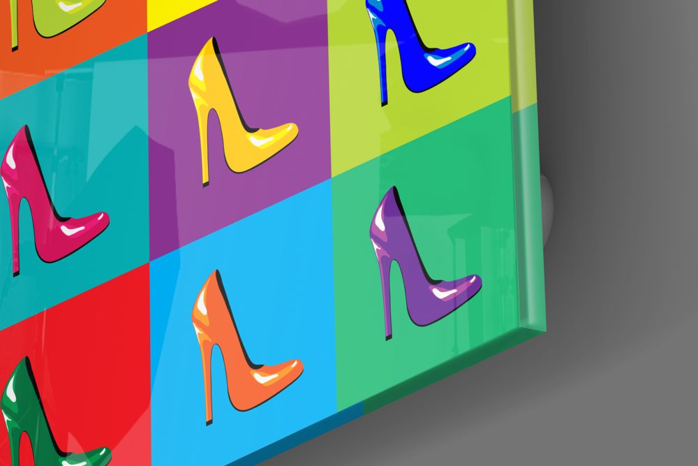 Angled perspective of colorful glass wall art displaying nine high-heeled shoes in vibrant colors against multicolored rectangular backgrounds.