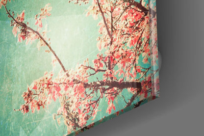 Cherry blossom glass wall art showing red blossoms and branches against turquoise background, angled three-quarter view.