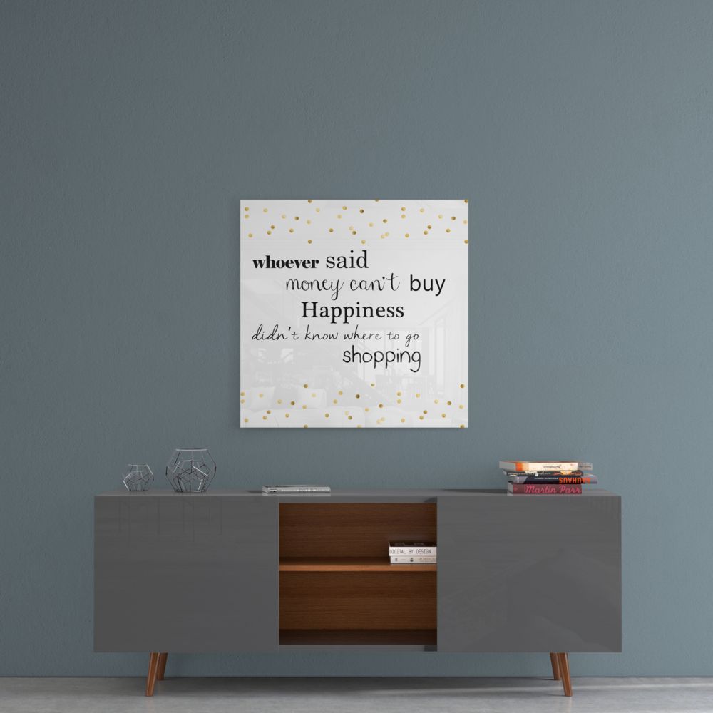 Glass wall art with gold polka dots displaying motivational shopping quote hangs above modern sideboard in styled room setting.