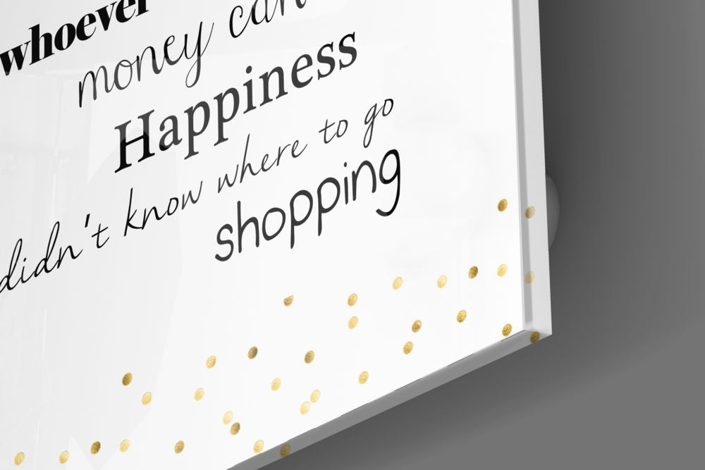 Close-up angled view of white glass wall art with black handwritten text and gold foil dots, displaying shopping-related phrases.
