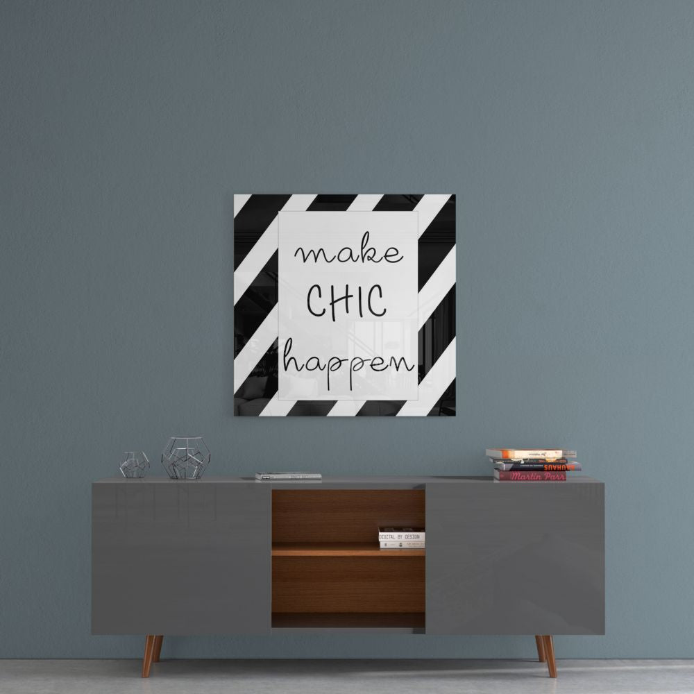 Square glass wall art with black and white diagonal stripes and handwritten text reading "make CHIC happen" displayed above a mid-century modern credenza.