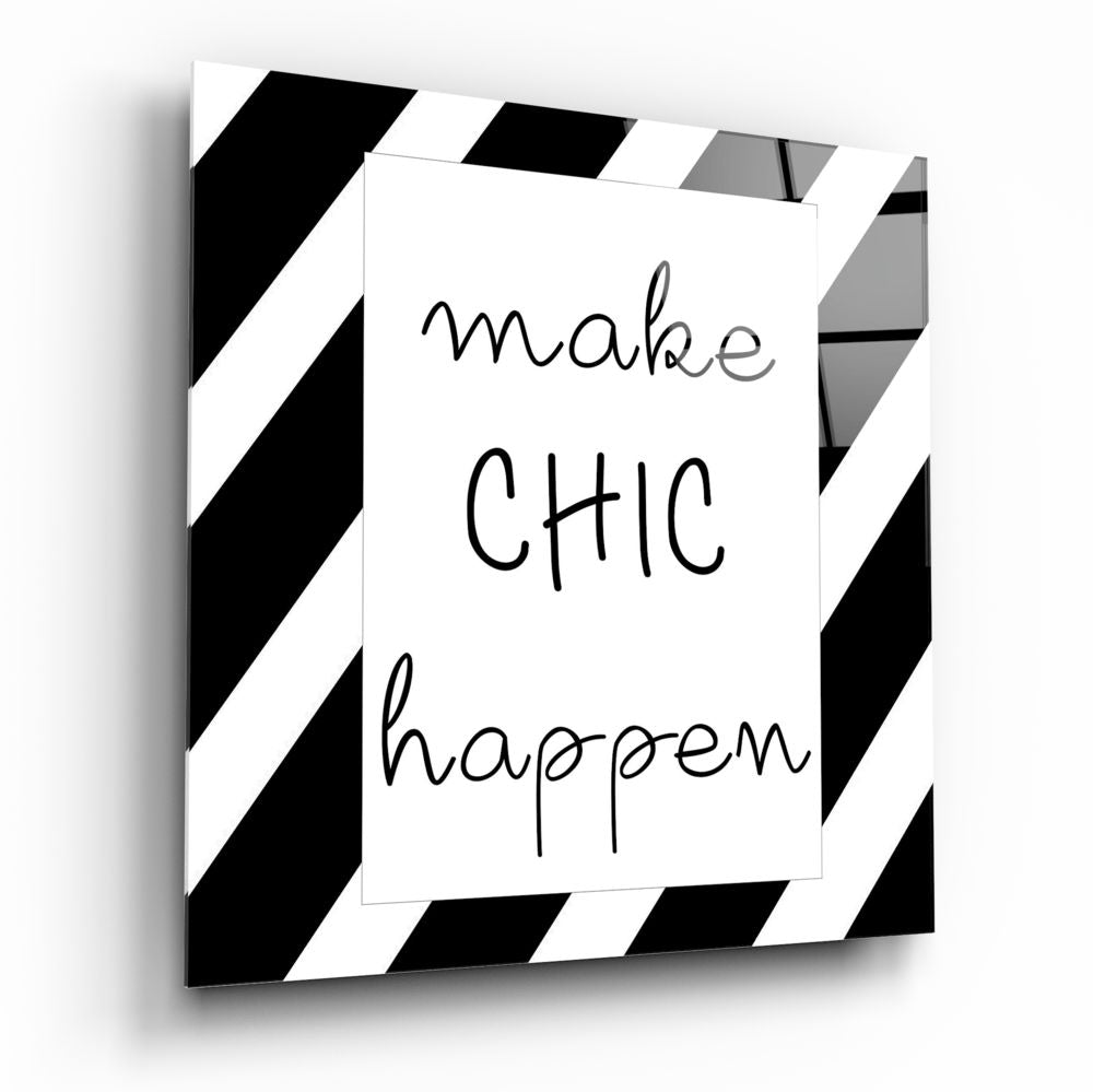 Three-dimensional angled view of glass wall art with black and white diagonal stripe border and handwritten text reading "make CHIC happen" on white center panel.