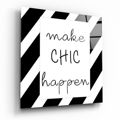 Three-dimensional angled view of glass wall art with black and white diagonal stripe border and handwritten text reading "make CHIC happen" on white center panel.