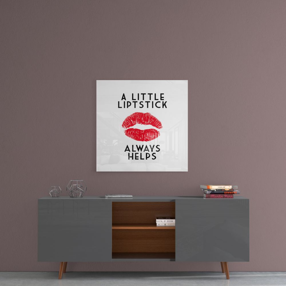 Square glass wall art with red lipstick kiss mark and black text reading "A LITTLE LIPSTICK ALWAYS HELPS" displayed above modern sideboard.