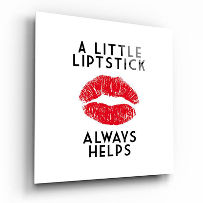 White glass wall art with black text reading "A LITTLE LIPSTICK ALWAYS HELPS" and a red lipstick kiss mark print in the center.