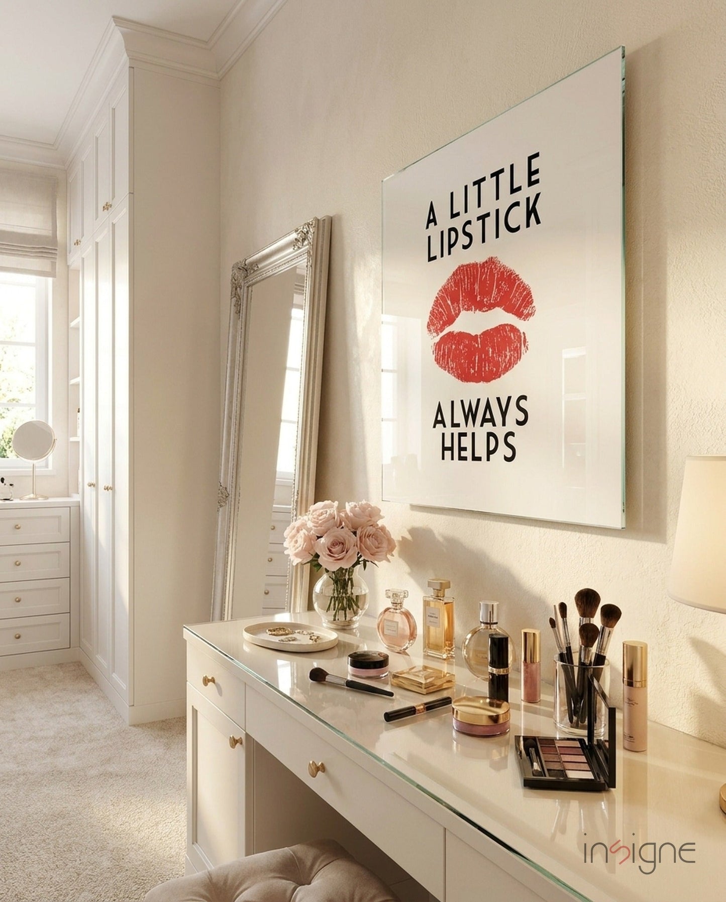 Framed glass wall art featuring red lips and black text reading "A Little Lipstick Always Helps" mounted above a white vanity table.