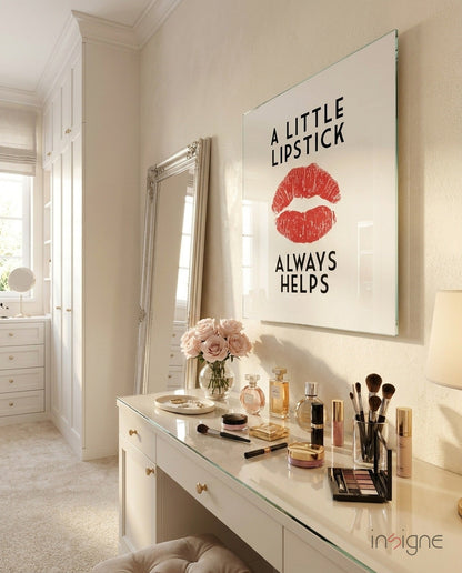 Framed glass wall art featuring red lips and black text reading "A Little Lipstick Always Helps" mounted above a white vanity table.
