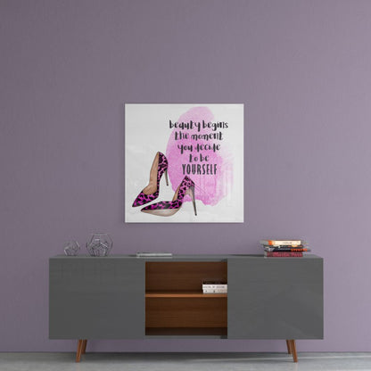Square glass wall art with pink watercolor silhouette, purple high heels, and black motivational text on lavender bedroom wall above gray dresser.