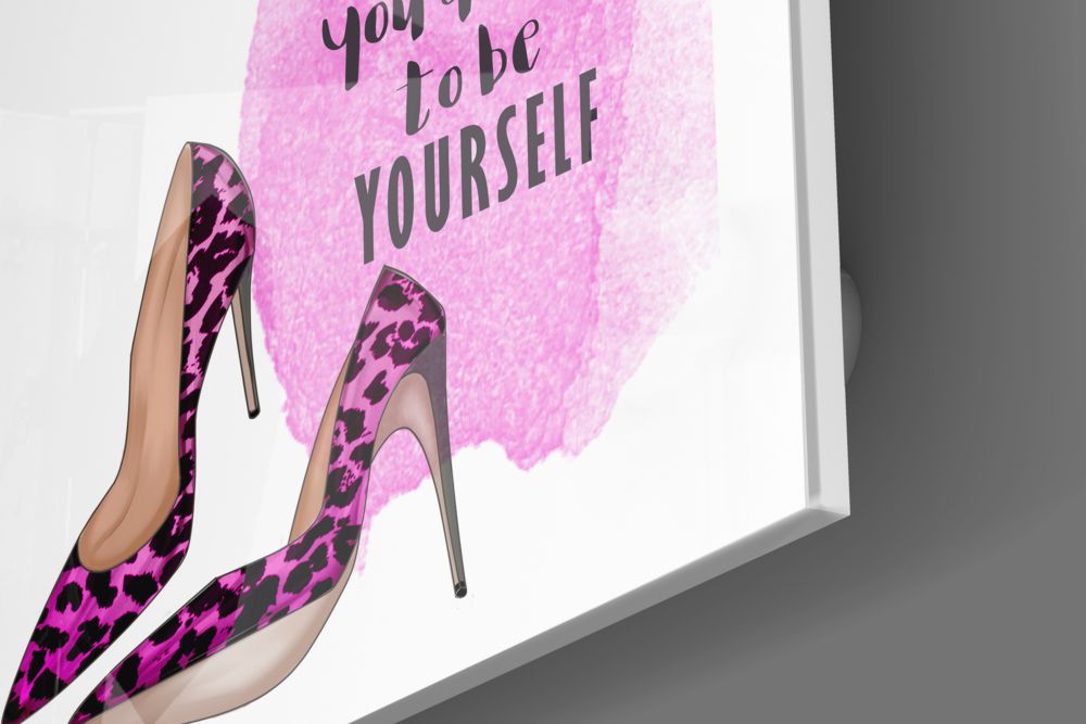 Angled view of glass wall art featuring pink watercolor background, black text reading "you to be yourself," and two pink leopard-print high heels.