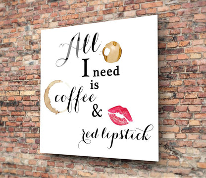 White glass wall art with black cursive text reading "All I need is coffee & red lipstick," decorated with coffee stain and lipstick mark illustrations, mounted on brick wall.