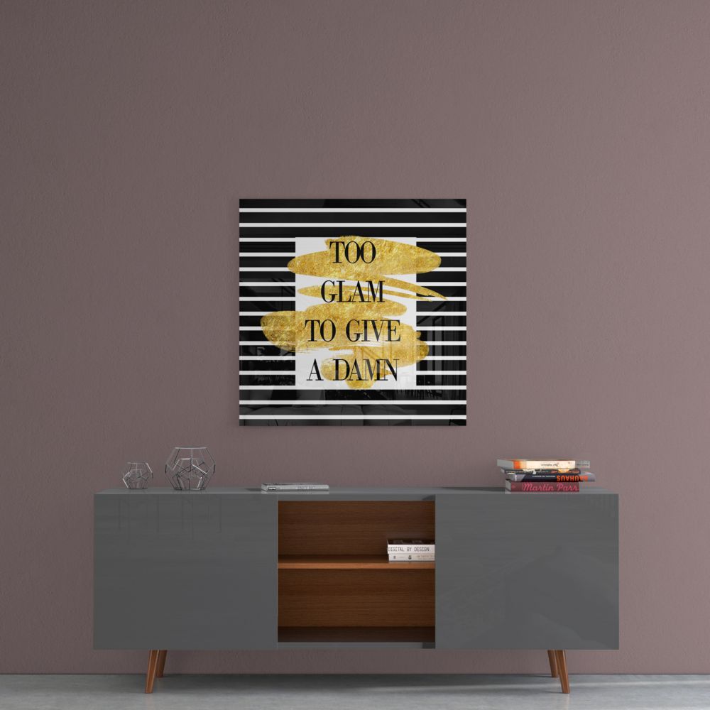 Gold foil and black striped glass wall art displaying "Too Glam to Give a Damn" text mounted above a gray sideboard.