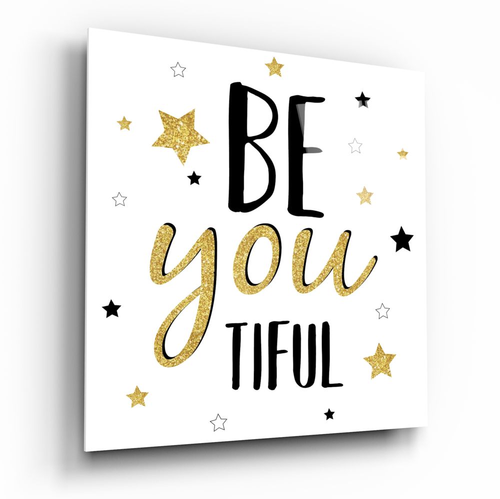 White glass wall art with black and gold glitter text reading "BE you TIFUL" surrounded by decorative stars in gold and black.
