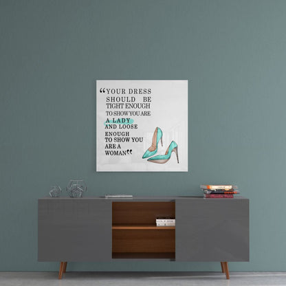 Glass wall art with fashion quote and turquoise high heels displayed above mid-century modern console table against blue-green wall.