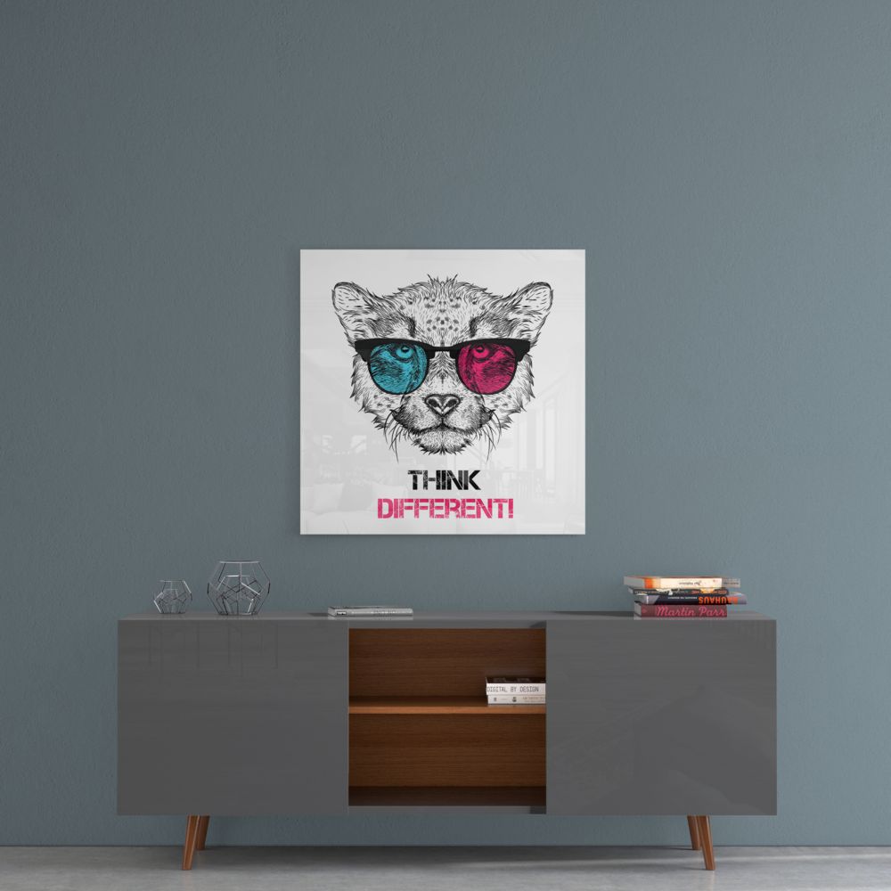 Square glass wall art with pen-drawn cat wearing colored sunglasses and "THINK DIFFERENT!" text, displayed above mid-century modern dresser.
