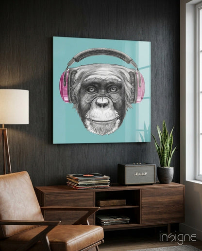 Pop art glass wall art featuring a chimpanzee wearing pink headphones against a turquoise background, displayed above a wooden console table in a modern room setting.