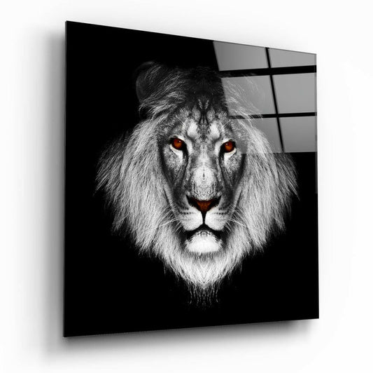 A framed glass wall art featuring a monochromatic lion with striking amber eyes against a black background, displayed at an angled perspective.