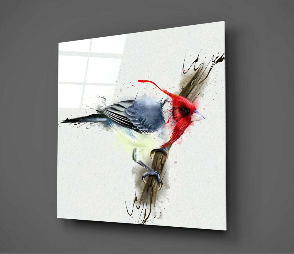 Glass wall art displaying a watercolor-style bird with red head and blue-gray body perched on a branch, mounted at an angle against a gray wall.