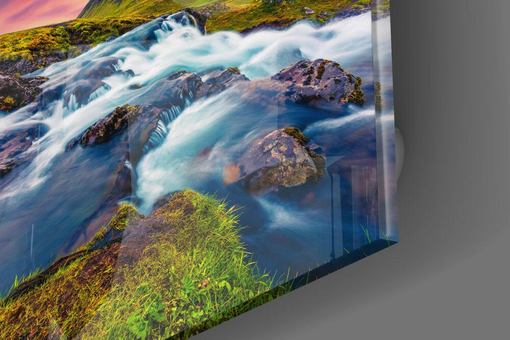 Cascading turquoise river with moss-covered rocks and green vegetation on glass wall art, angled view showing depth and reflection.