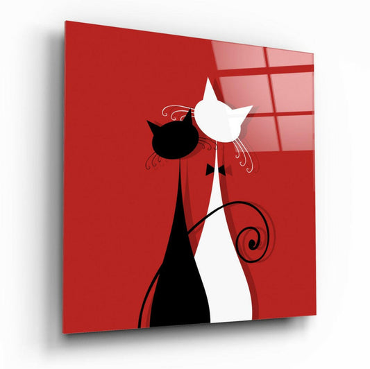 Angled perspective view of red glass wall art featuring black and white stylized cat silhouettes with decorative swirls against a red background.