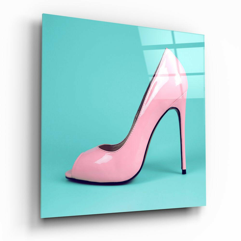 Pink patent leather high-heeled pump with black stiletto heel displayed against turquoise background on glass wall art panel.