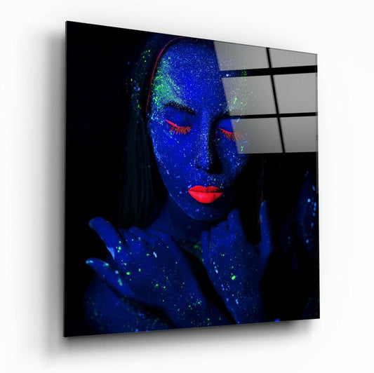 Woman with blue UV body paint and red lips displayed on glass wall art panel, shown at angled perspective with shadow.