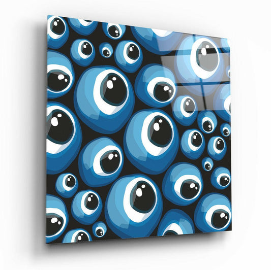 Angled perspective of a square glass wall art panel displaying a dense pattern of blue and white evil eye beads against a black background.
