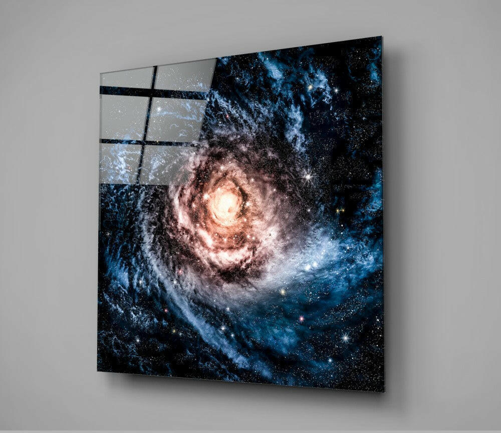 Angled view of glass wall art displaying a spiral galaxy with blue and pink nebula clouds against black space, mounted on gray wall with grid pattern overlay.
