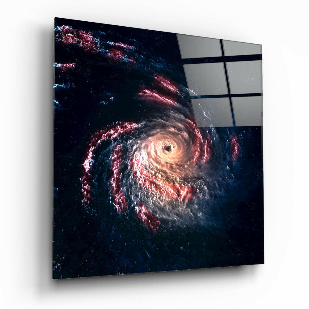 Angled view of square glass wall art depicting a glowing spiral galaxy with red and white clouds against dark space, with gray panels visible in upper right corner.