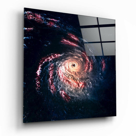 Angled view of square glass wall art depicting a glowing spiral galaxy with red and white clouds against dark space, with gray panels visible in upper right corner.